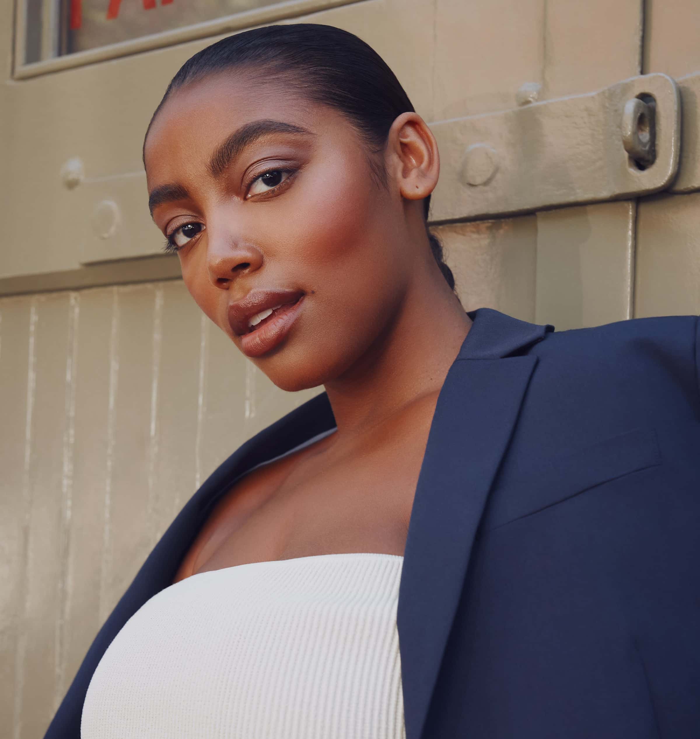 A young, black woman wears a navy blue suit.