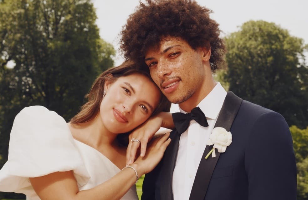 Soft smile closeup wedding photo with one shoulder puff sleeve wedding dress & navy tuxedo for wedding.