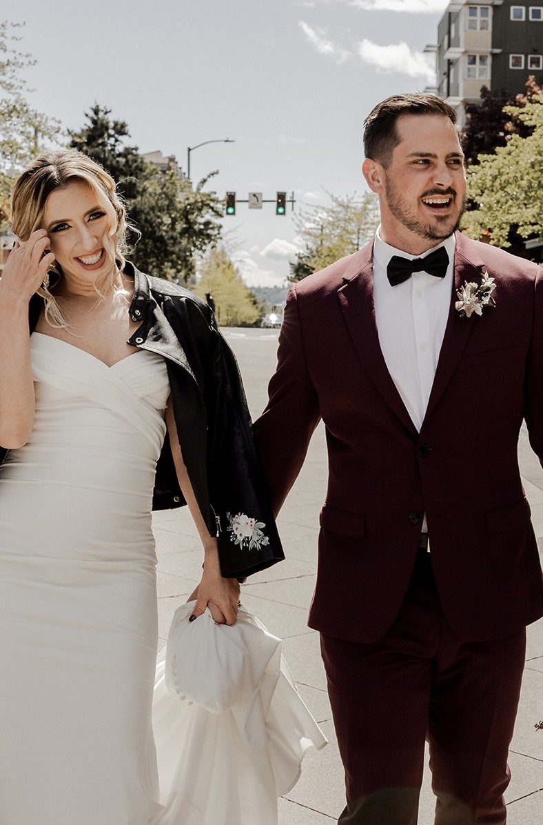 Fun, edgy wedding shoot with burgundy suit and the bride in a wedding gown and biker jacket.