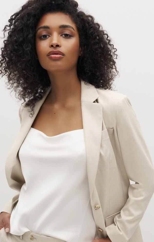 Open women's tan suit jacket with silk shell top.