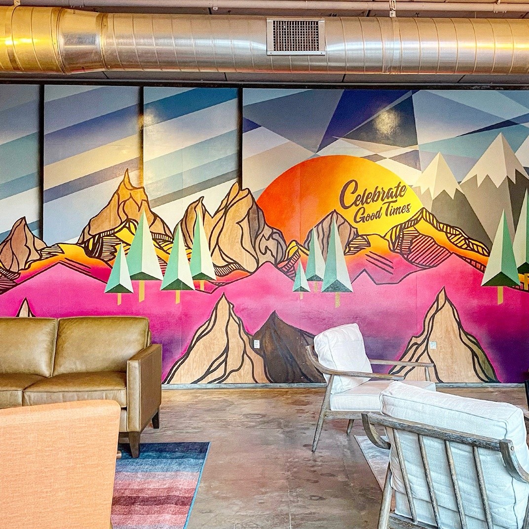 Graphic mountain mural reading, “celebrate good times” in Denver suit store with lounge & suit fitting areas.