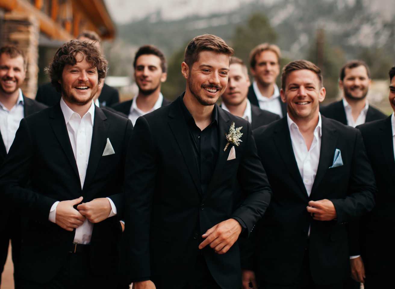 A groom walks with his groomsmen in SuitShop's classic black suits.