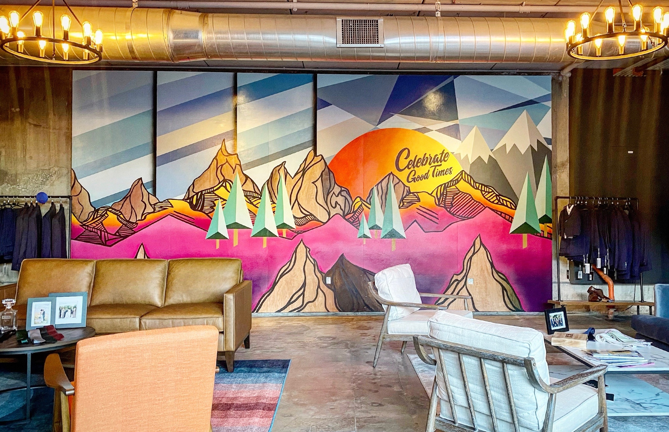 Mountain mural by Pat Milbery reading, “celebrate good times” in Denver suit store for suit fittings.
