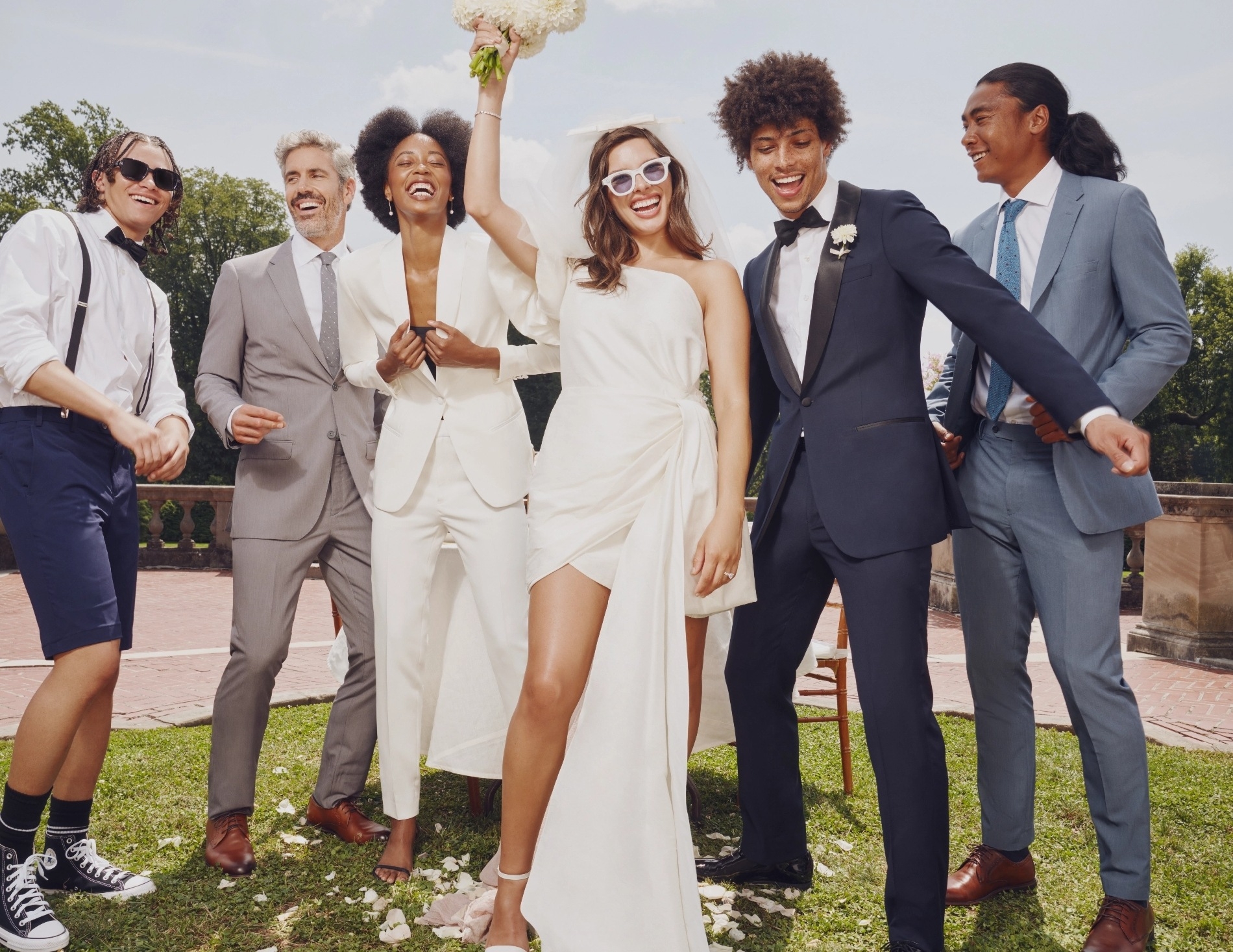 Mixed-gender wedding party celebrating in stylish wedding suits and tuxedos.