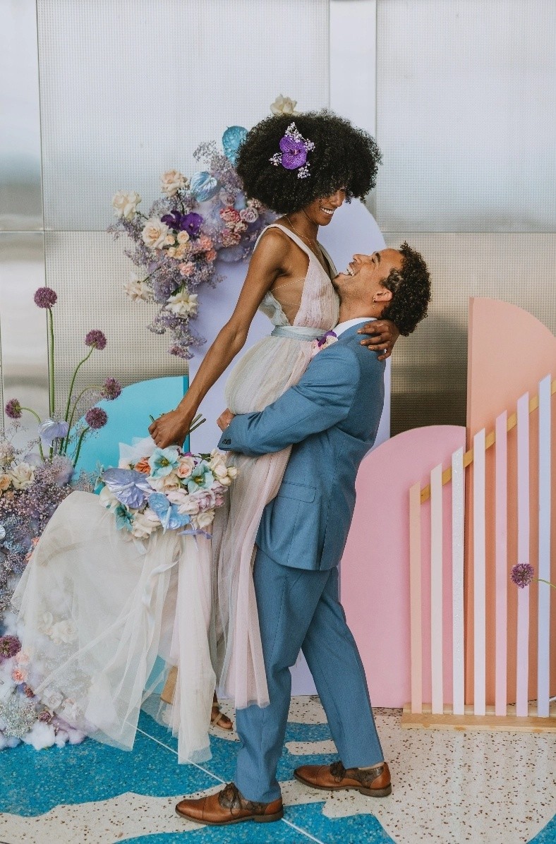 Whimsical styled shoot with light blue wedding suit, blush wedding gown, and pastel backdrop.