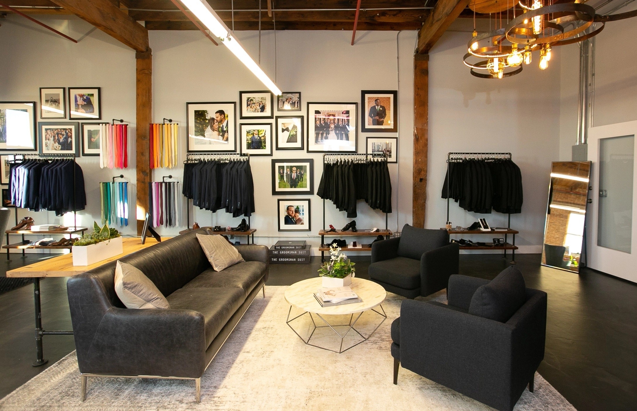 Interior of suit store in Chicago with black suits, grey suits, colorful accessories, and lounge area.