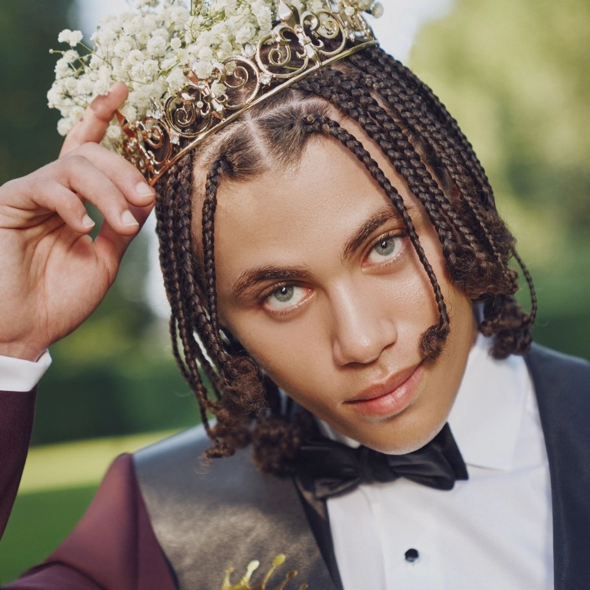 Closeup image of a prom suit with flower crown, black bow tie, tuxedo shirt for prom & maroon tuxedo.