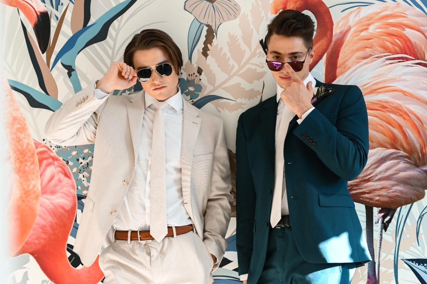 Light tan suit for prom & brown belt, teal prom suit & cool sunglasses with prom photo backdrop.
